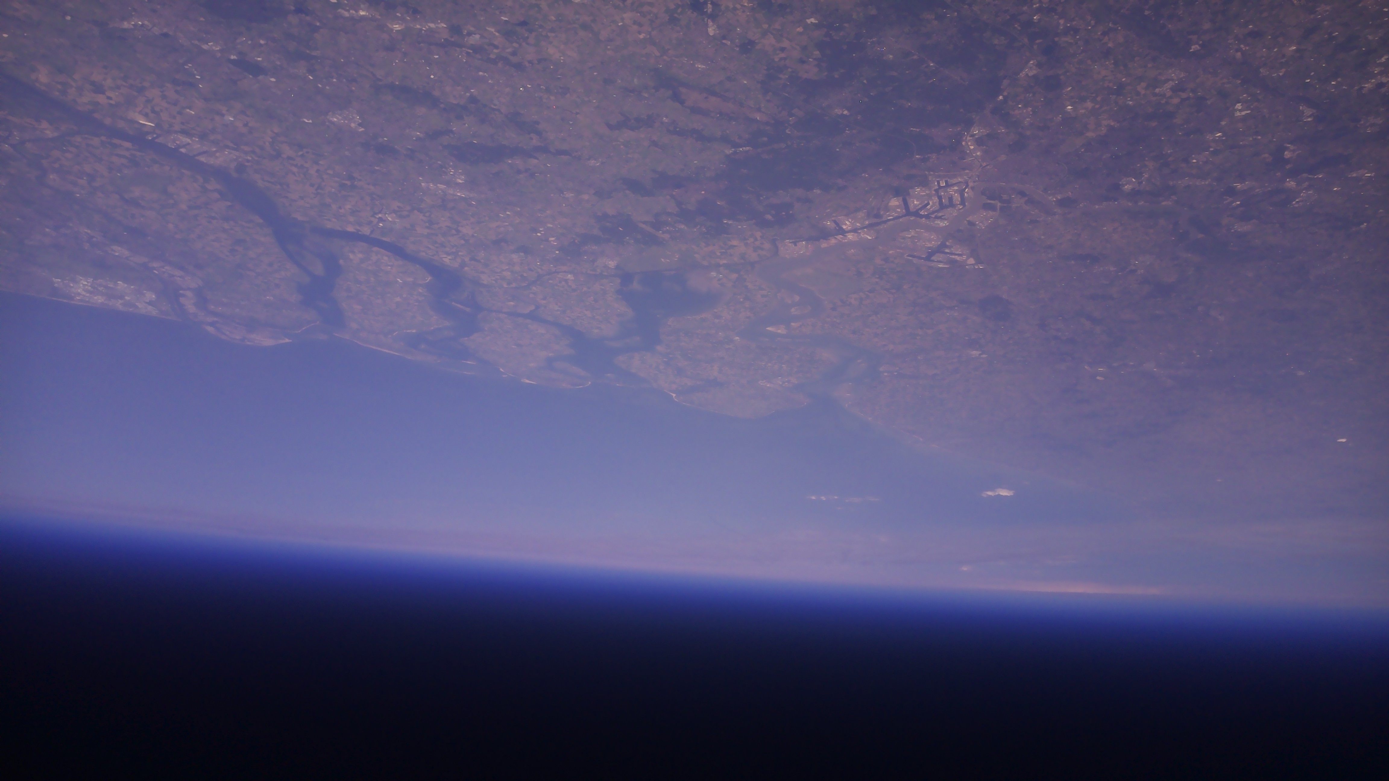 The Earth from 37 km altitude, showing Belgium and the Netherlands’ coastline with a few clouds overhead.